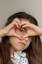 Pretty Young Girl Making A Heart Shape Around Her Blue Eye