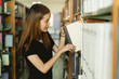 © Pormezz - Asian student choosing book in the shelf in library.