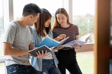 Canvas Print - Group of asian students researching data for homework assignment in library.