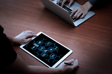 top view of two colleagues discussing data with new modern computer laptop and pro digital tablet on wooden desk as concept