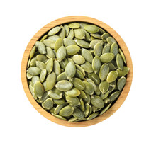 Dry pumpkin seeds in wooden bowl on white background