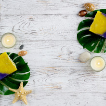 Yellow Handmade Soap With Monstera Leaf, Candles, Stones And Starfish On White.