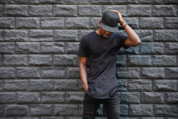 Wall Mural - Handsome african american man in blank black t-shirt standing against brick wall