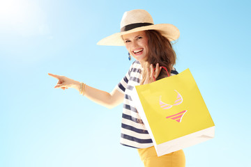 Wall Mural - woman with yellow shopping bag with bikini pointing at something