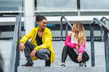 smiling young multiethnic couple dancing on stairs at urban street