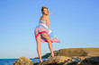 © indigo_nifght - sexy blonde on a rocky coast, playing with a dress developing in the wind, turning back.