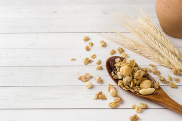 Dry Breakfast of oat flakes, granules and nuts. Muesli on a light table in a wooden spoon and ears. Copy space