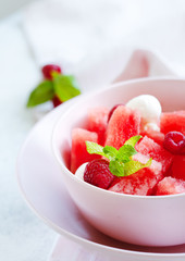 Watermelon salad with raspberry and mozzarella in pink bowl on white table