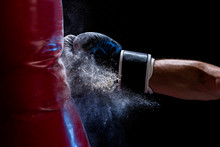 Close-up Hand Of Boxer At The Moment Of Impact On Punching Bag Over Black Background