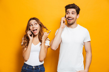 Poster - Happy young couple talking on mobile phones