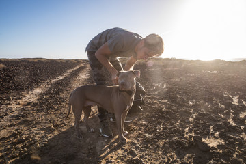 couple with young caucasian male and beautiful amstal dog prepare for a party or nice leisure activity together. friendship and love with the dog best friend. outdoor desert location and sunset time