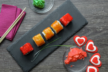 Japanese sushi rice and sea bass, shrimp and smoked eel with caviar of flying fish with Philadelphia cheese, chopsticks on a black plate of shale