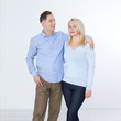 © missty - Full length portrait of happy mature couple standing with hands in pockets over white background