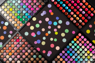 Colorful make-up palettes and colorful confetti on black background