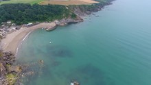 4K Cornwall Aerial Over Par Sands Beach And Surrounding Coast And Polkerris Harbour And Beach. Flying Over Fields With Sheep And Cows With Lush Green Grass Along The South West Coast Path.