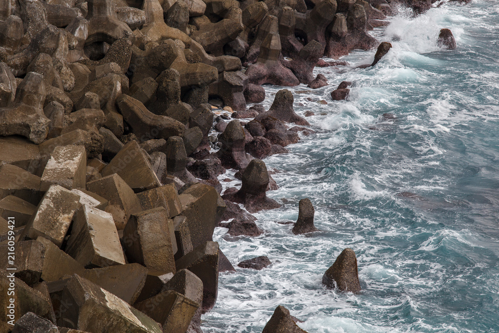 Tetrapod concrete blocks protecting a seawall along the coastline in Tamsui, Taipei Taiwan. Assortment of interlocked tetrahedral shapes and strong ocean waves. Coastal Engineering Structure