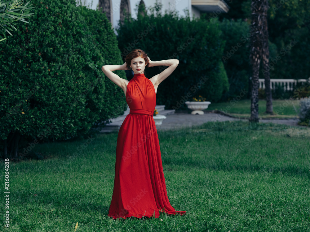 beautiful woman in red evening dress in the park