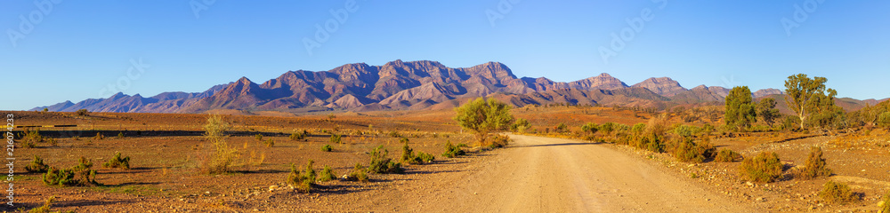 Obraz na płótnie Gravel countryside road leading to rugged peaks of Flinders Ranges mountains in South Australia w salonie
