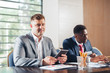 © fotofabrika - Portrait of two business partners sitting at a table together and working.