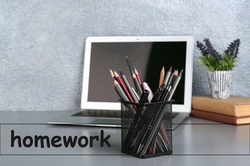 Wall Mural - Pencils and pens in holder with laptop on table. Preparation of homework assignment