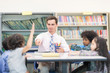 © Nattanon - Happy Children and teacher in Learning Class at Library. Boy raised hand up his hand to answer a question from teacher. Setup studio shooting.