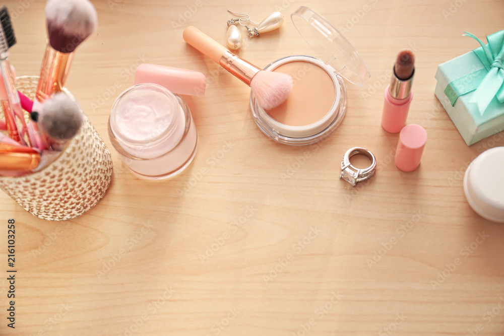 Set of decorative cosmetics with makeup brushes on table