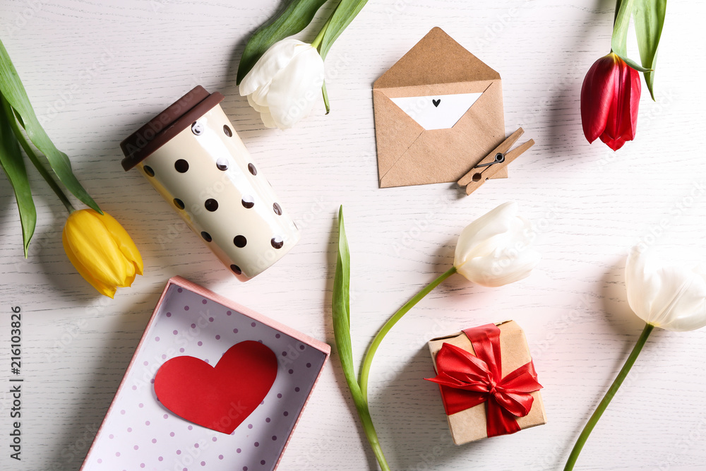 Flat lay composition with gift box, cup of coffee and beautiful flowers on light background