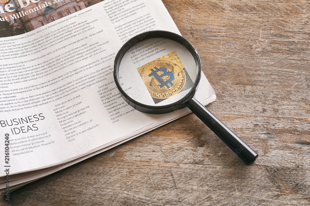 Magnifying glass and newspaper on wooden background