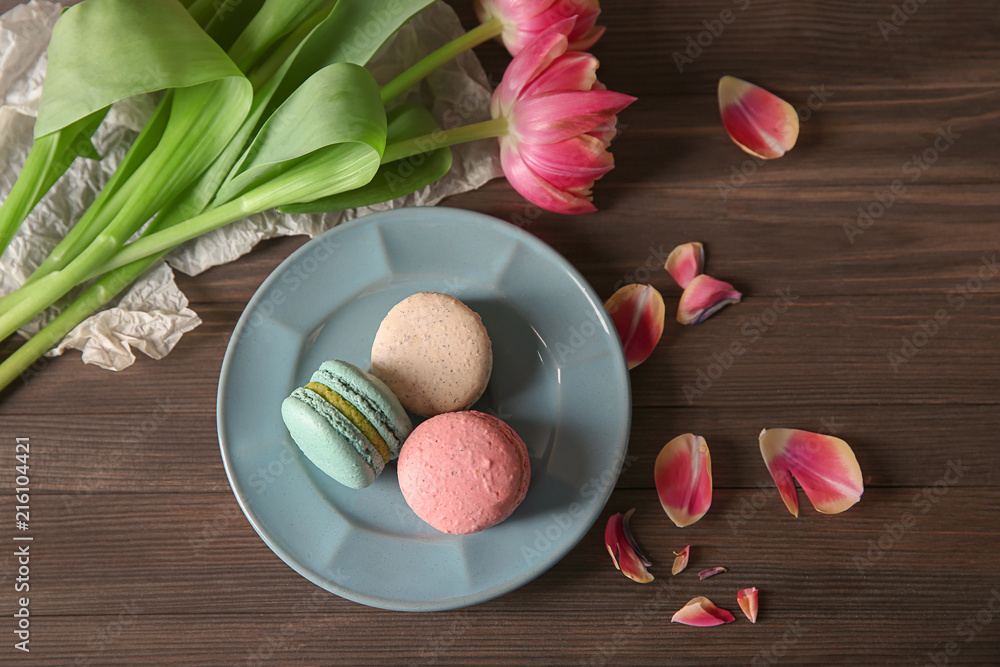 Flat lay composition with tasty macarons and tulips on wooden background
