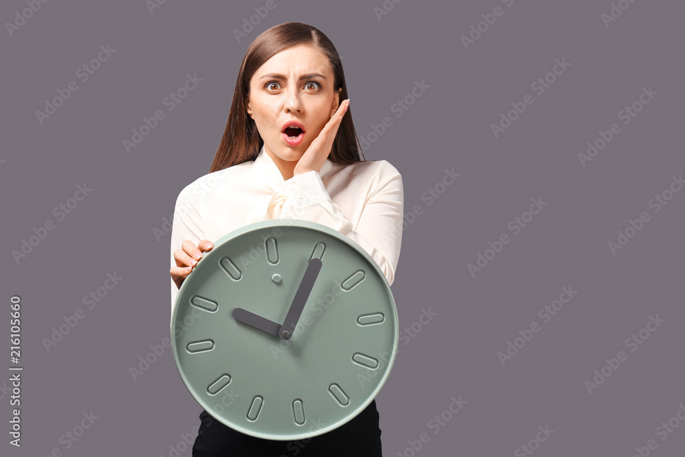Troubled woman with clock on grey background. Time management concept