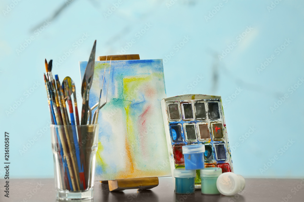 Glass with tools, paints and picture on table