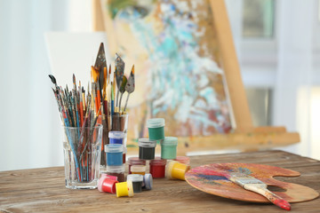 Set of tools and paints of professional artist on table in workshop