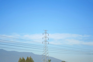 High voltage pole and landscape of rural on bright blue sky background