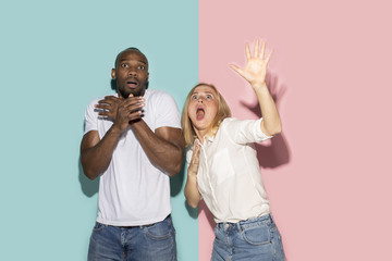 Wall Mural - Portrait of the scared couple on pink and blue studio background