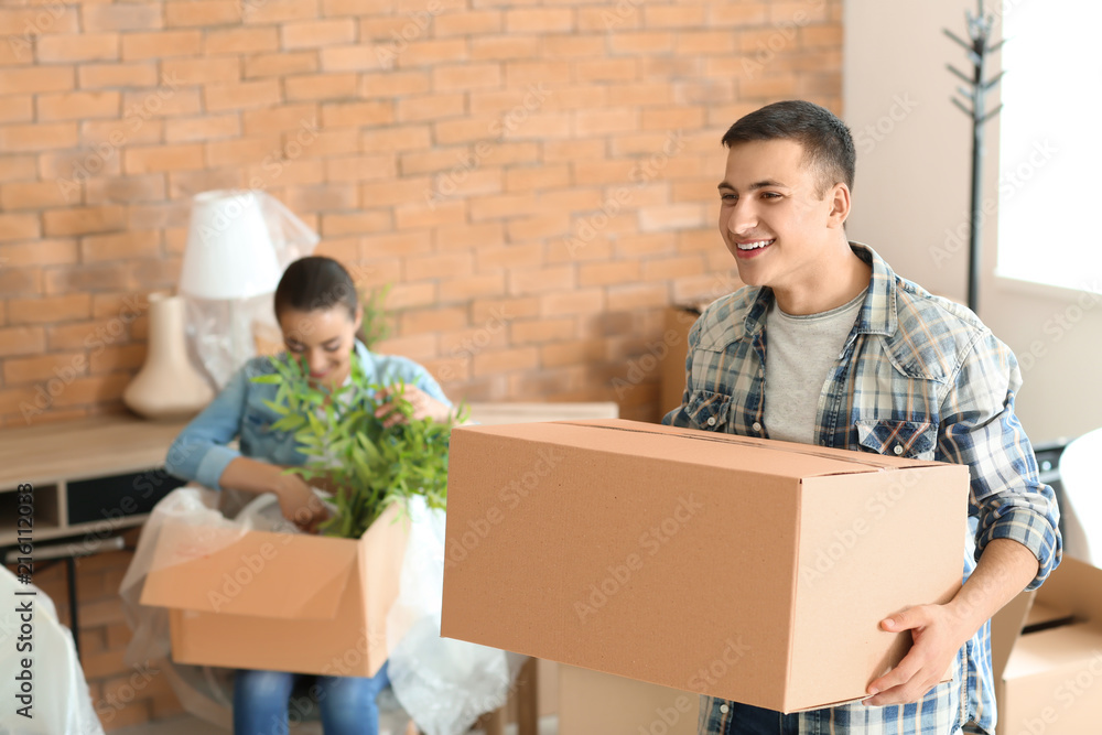 Young man with box indoors. Moving into new house