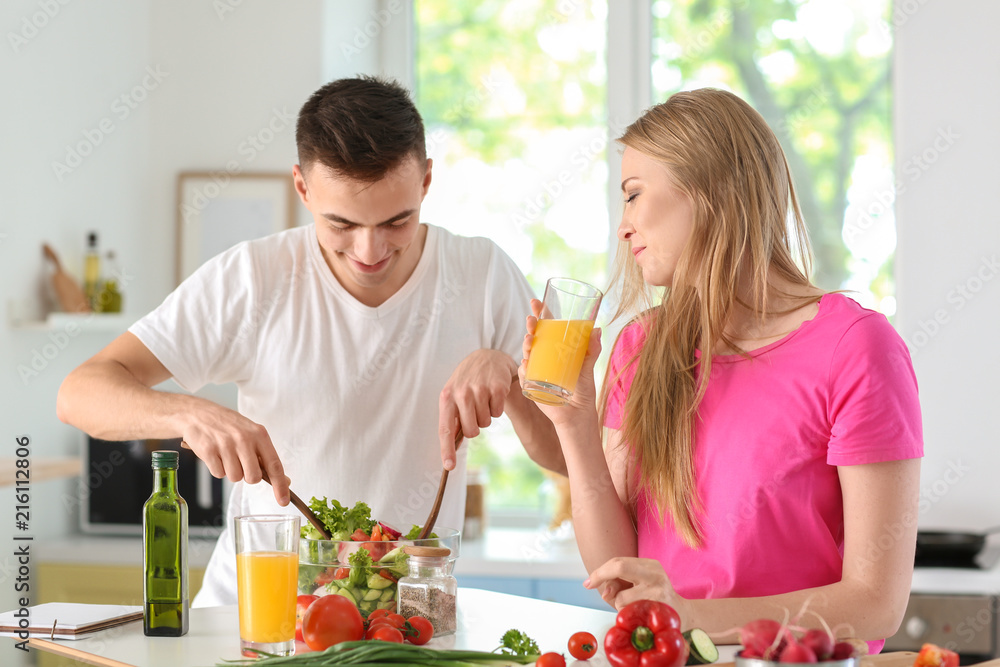 Young man cooking with his girlfriend in kitchen