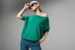 © LIGHTFIELD STUDIOS - beautiful female model in sunglasses and green sweater posing isolated on grey background