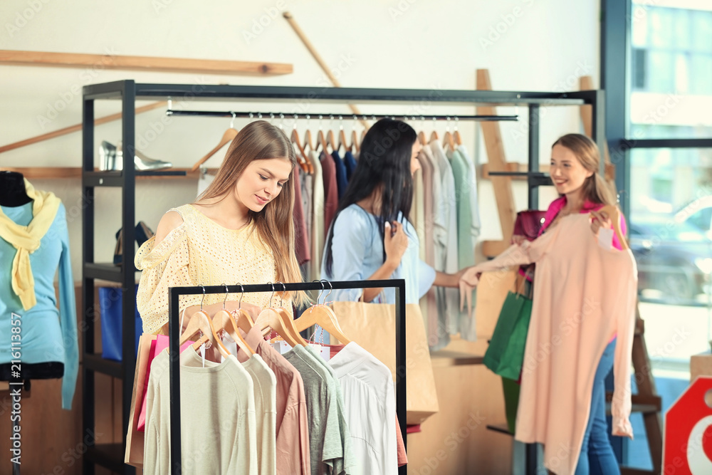 Beautiful young girl choosing clothes in shop