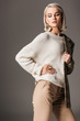 © LIGHTFIELD STUDIOS - fashionable girl posing in white sweater and tweed jacket on one shoulder, on grey
