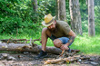 © be free - Ultimate guide to bonfires. How to build bonfire outdoors. Arrange the woods twigs or wood sticks standing like a pyramid and place the leaves under. Man straw hat prepares bonfire in forest