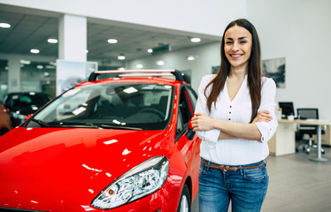 Wall Mural - Smiling young beautiful woman in dealership. Beautiful woman buying a new car for job and travel in dealership, girl customer