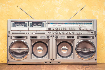 Poster - Retro outdated portable stereo boombox radio receiver with cassette recorder from circa 80s front concrete textured yellow wall background. Listening music concept. Vintage old style filtered photo