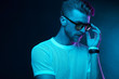 © monchak - Neon light studio portrait of attractive male model with mustaches and beard in sunglasses and white t-shirt