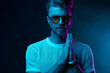 © monchak - Neon light studio portrait of attractive male model in sunglasses and white t-shirt