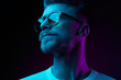 canvas print picture - Neon light studio close-up portrait of serious man model with mustaches and beard in sunglasses and white t-shirt