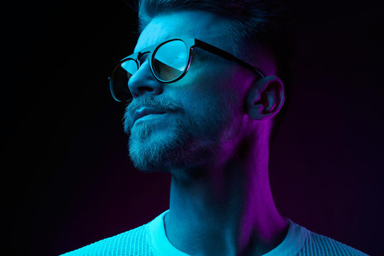 neon light studio close-up portrait of serious man model with mustaches and beard in sunglasses and 