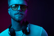© monchak - Neon light portrait of smiling man with headphones on neck,in sunglasses and white t-shirt.
