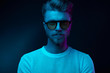 © monchak - Neon light portrait of serious man model with mustaches and beard in sunglasses and white t-shirt