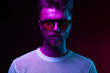 © monchak - Neon light portrait of serious man model with mustaches and beard in sunglasses and white t-shirt