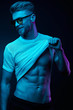 © monchak - Neon light portrait of sexy smiling man in yellow glasses, pulling up t-shirt, showing abs